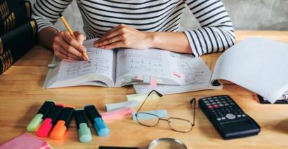 Student revising and completing secondary science homework with highlighters, notebooks and calculator
